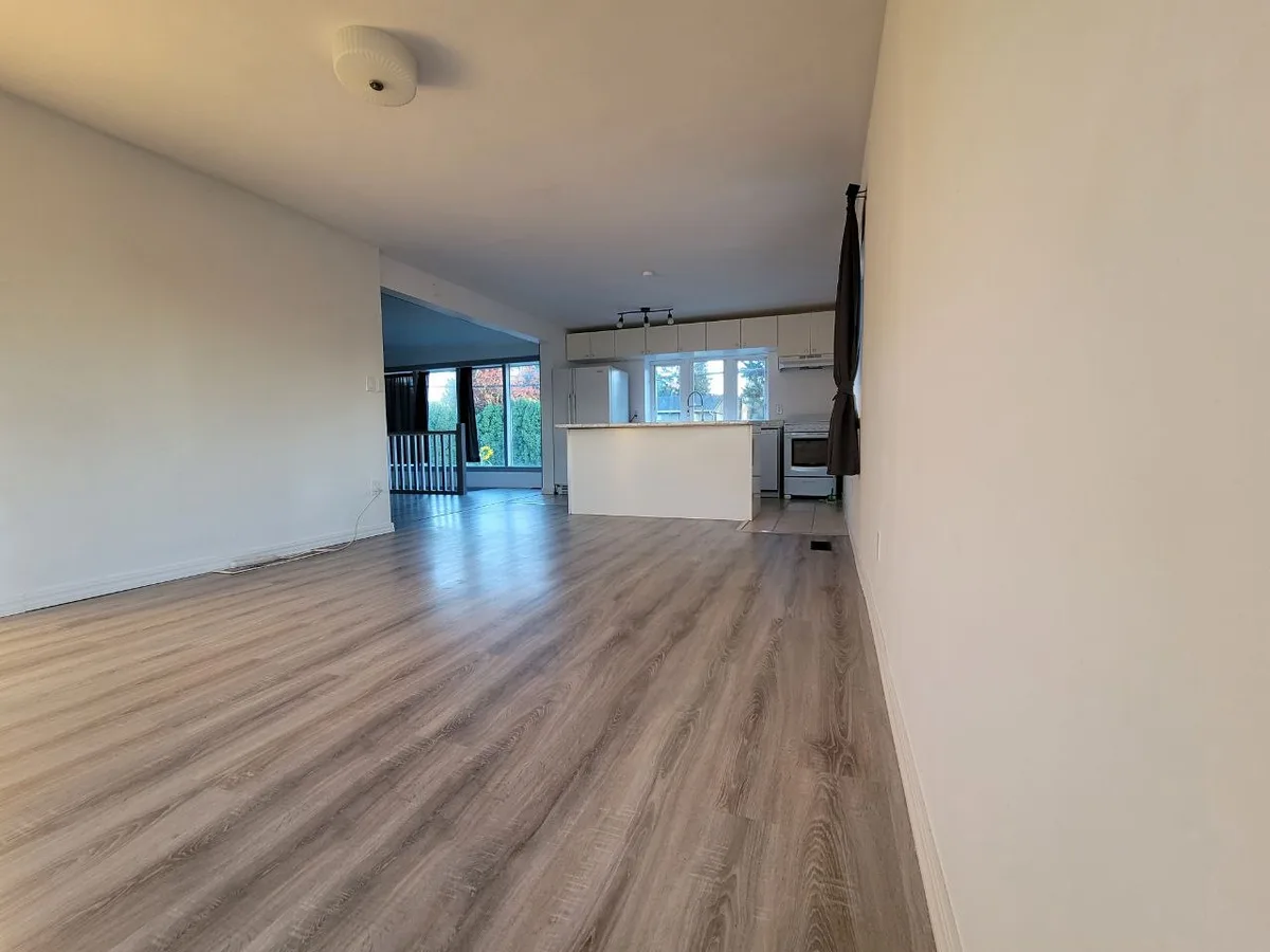 Living area mid flooring install with underlayment and plank boxes, then finished open light-oak living space.