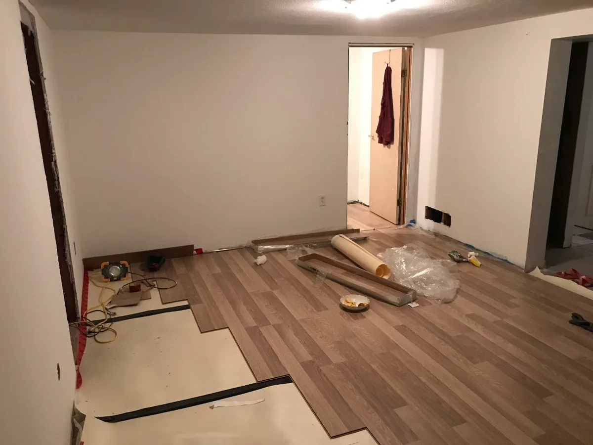 Metro Vancouver Interior: Flooring, Kitchen & Bath — before — Living area mid flooring install with underlayment and plank boxes, then finished open light-oak living space.