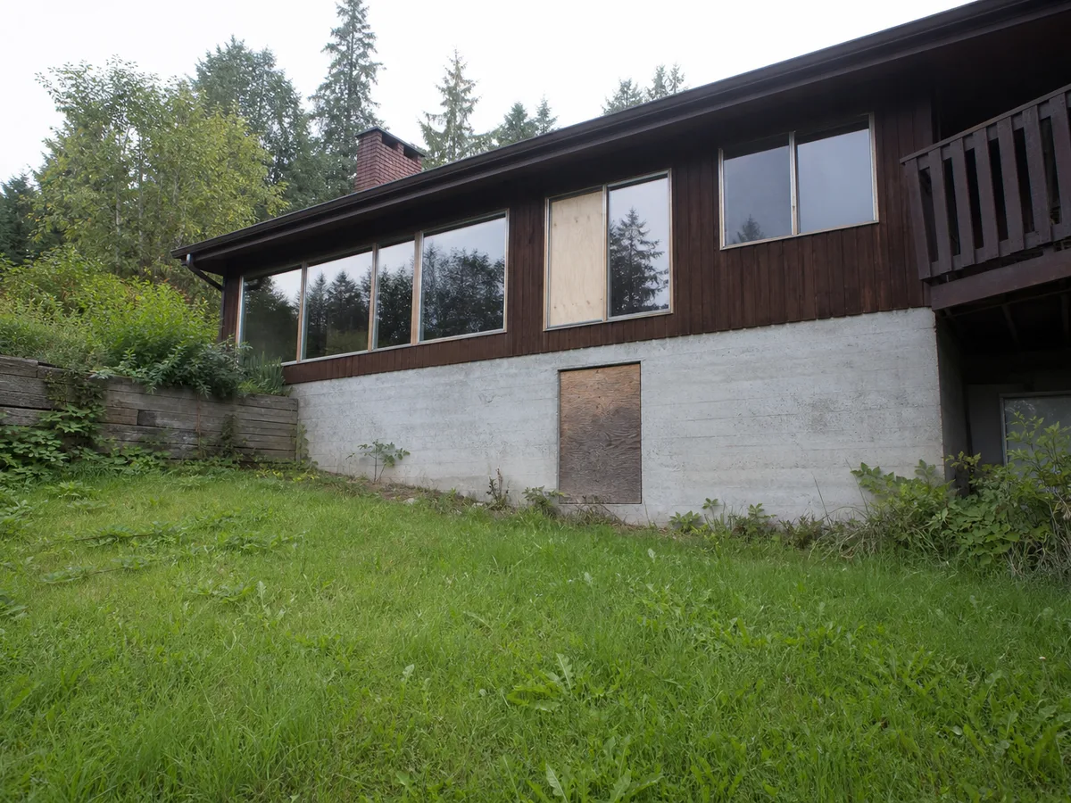 Sloped backyard and bare foundation wall before the walk-out entrance was built, North Vancouver