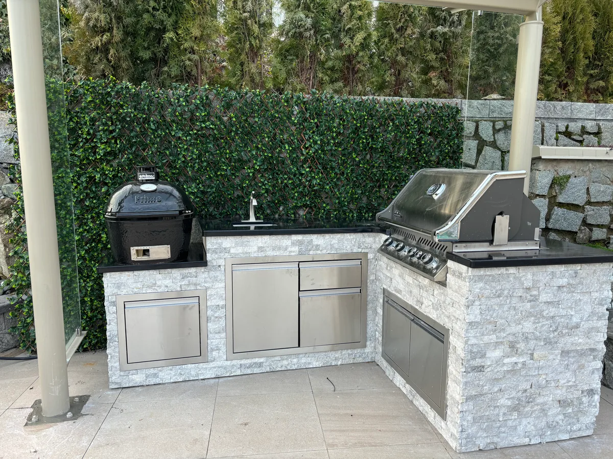Same stone-wall cooking corner: portable grill and side table, then built-in outdoor kitchen with stainless appliances and stone veneer.
