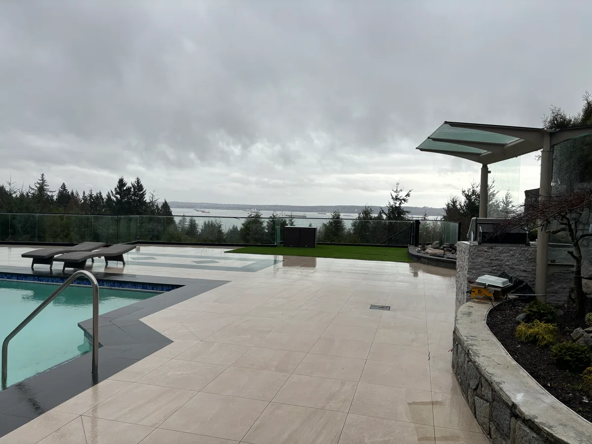 Main patio during glass-railing and canopy material staging, then finished pool-and-patio composition overlooking the view.
