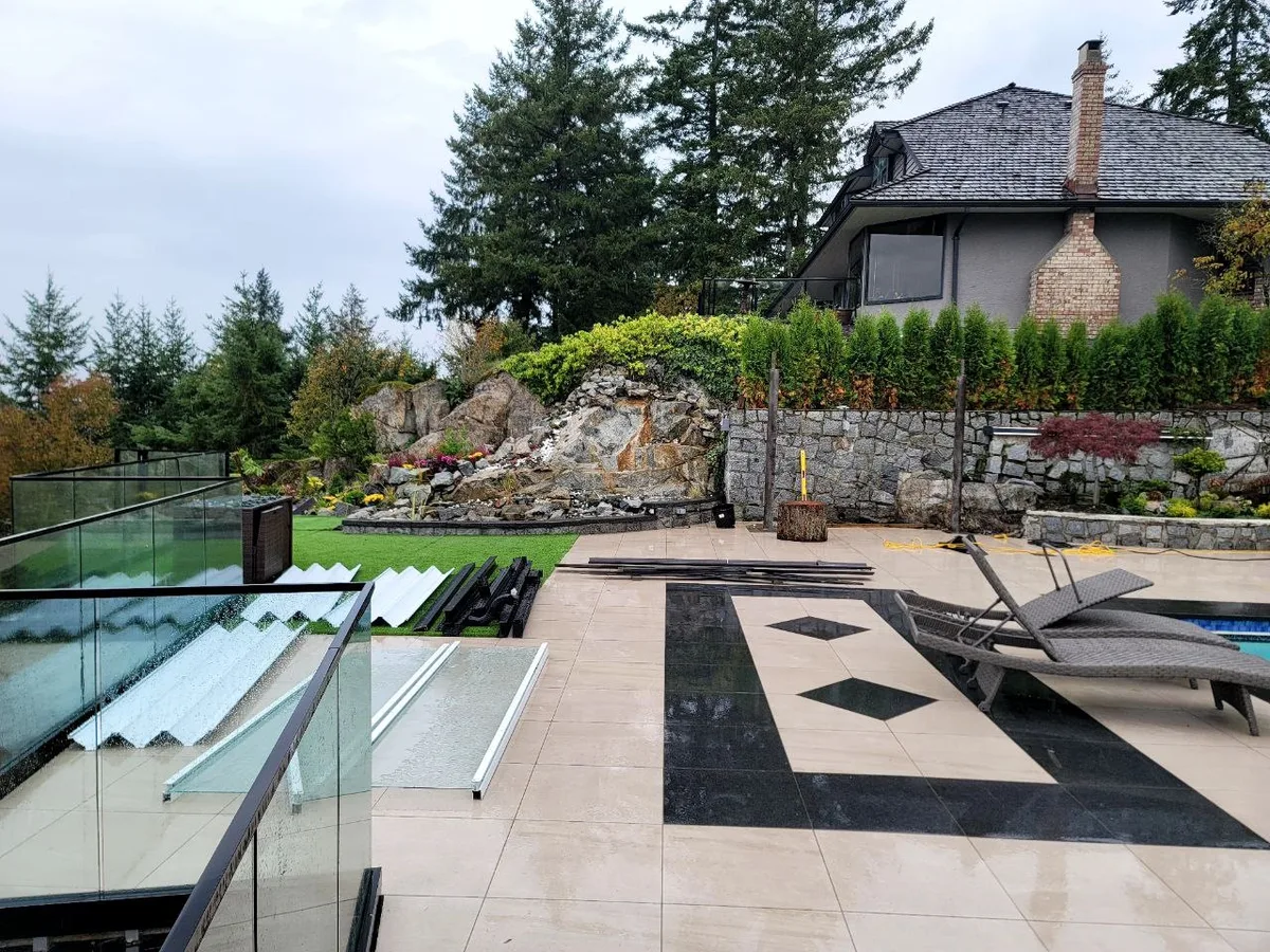 West Vancouver Patio, Pool Deck & Glass Railings — before — Main patio during glass-railing and canopy material staging, then finished pool-and-patio composition overlooking the view.