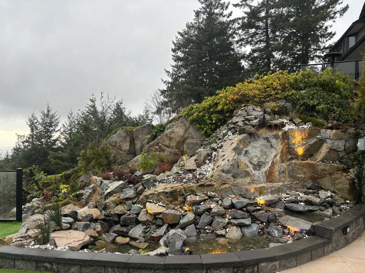 Waterfall rockwork with liner, pump parts, and tools exposed, then finished cascading feature with integrated landscape lighting.
